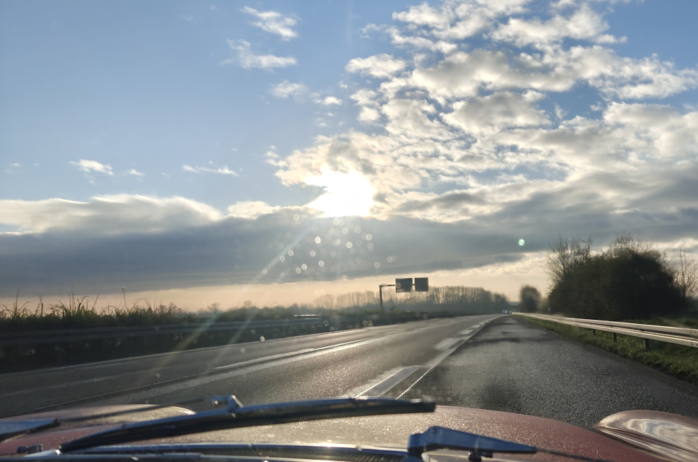 A red Volvo 1800E drives on the motorway towards the setting sun